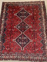 PERSIAN RED GROUND HANDMADE WOOL RUG, triple medallion centre, geometric border, 210 x 168cms