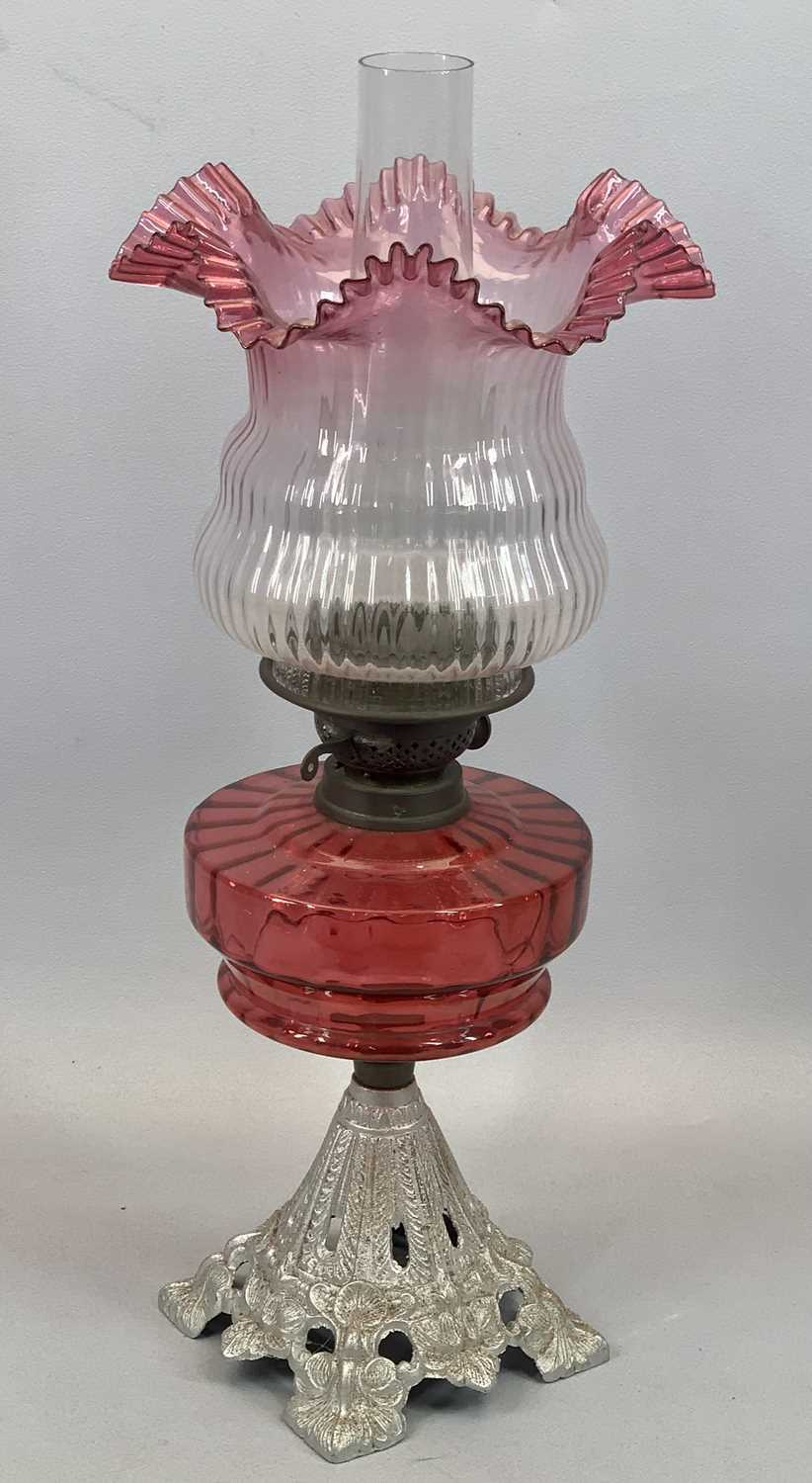 IRON BASED OIL LAMP having a fine cranberry glass reservoir and shade, 57cms total Provenance: