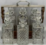 20TH CENTURY SILVER PLATED & MAHOGANY THREE-BOTTLE TANTALUS & THREE FURTHER CUT GLASS DECANTERS, the