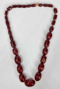 CHERRY AMBER SINGLE STRAND NECKLACE of graduating oval and barrel shape beads, 33mms largest oval,