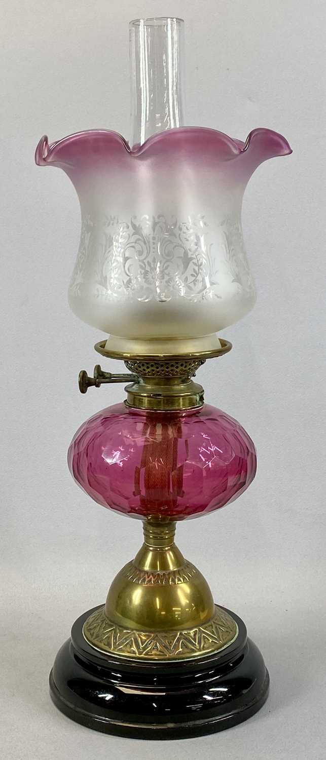 VICTORIAN OIL LAMP, with black ceramic base, embossed brass column, facetted circular cranberry