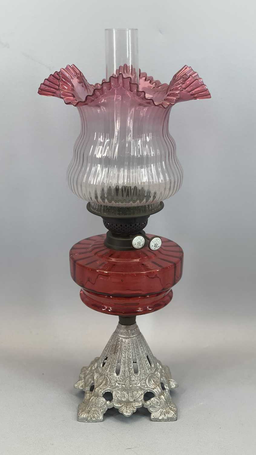 IRON BASED OIL LAMP having a fine cranberry glass reservoir and shade, 57cms total Provenance: - Image 2 of 3