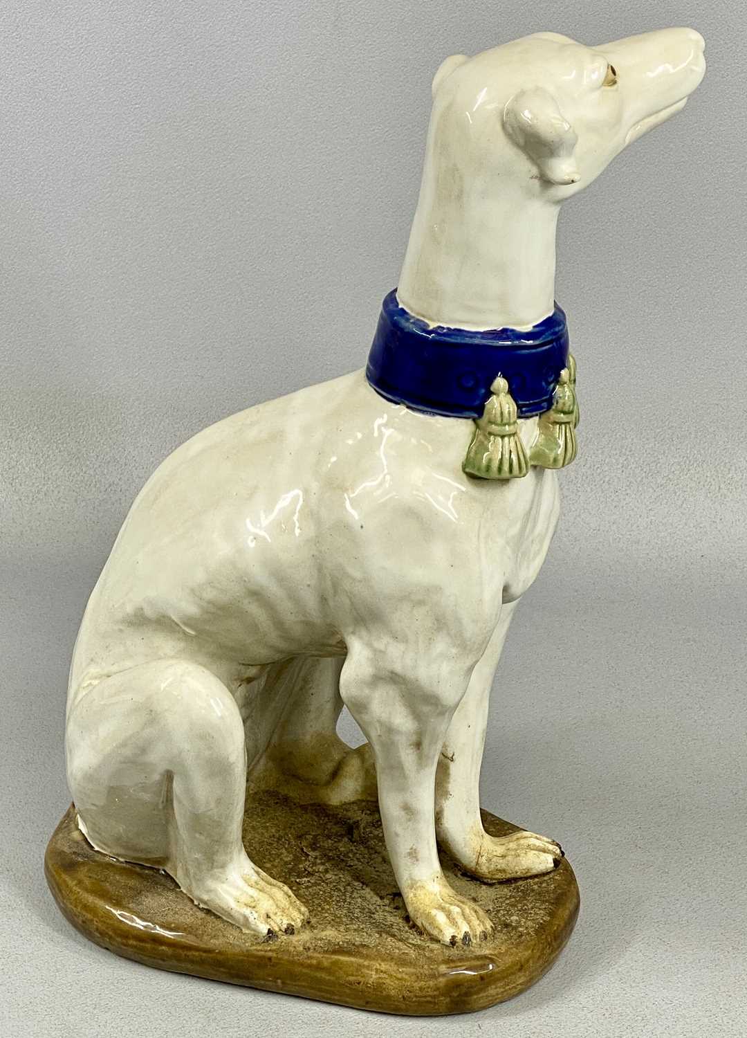 PAIR OF ITALIAN MAJOLICA GREYHOUNDS 20th century, seated and in cream glaze with tassled blue - Image 4 of 5
