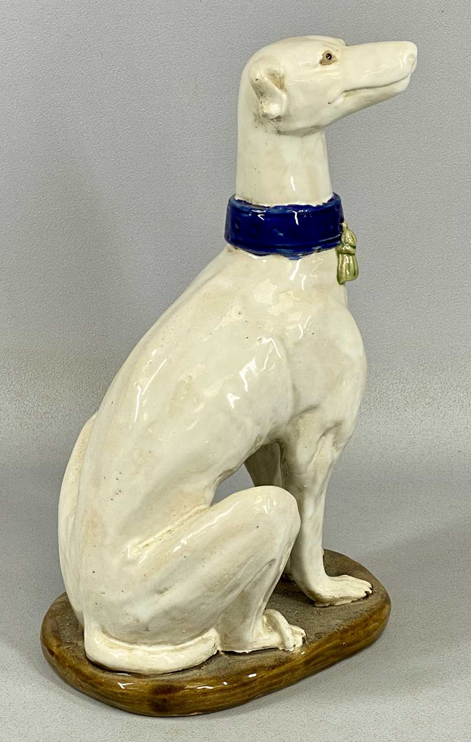 PAIR OF ITALIAN MAJOLICA GREYHOUNDS 20th century, seated and in cream glaze with tassled blue - Image 5 of 5