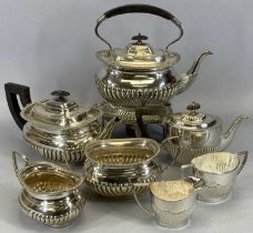 TWO EPNS GADROONED TEA SERVICES comprising a three-piece service with similar spirit kettle on