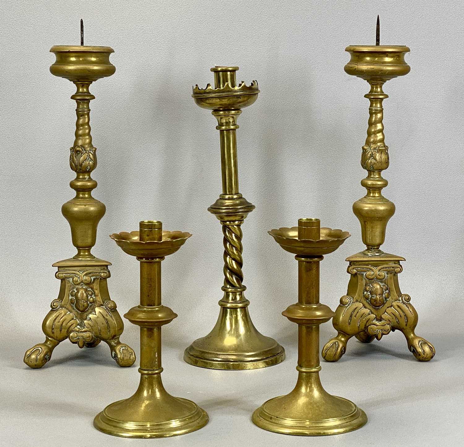 PAIR OF VICTORIAN CAST BRASS PRICKET CANDLE HOLDERS, the trefoil form bases cast with mask heads and