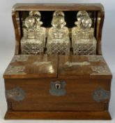 EDWARDIAN WALNUT THREE BOTTLE TANTALUS, with EPNS mounts, lidded compartments for cigars and