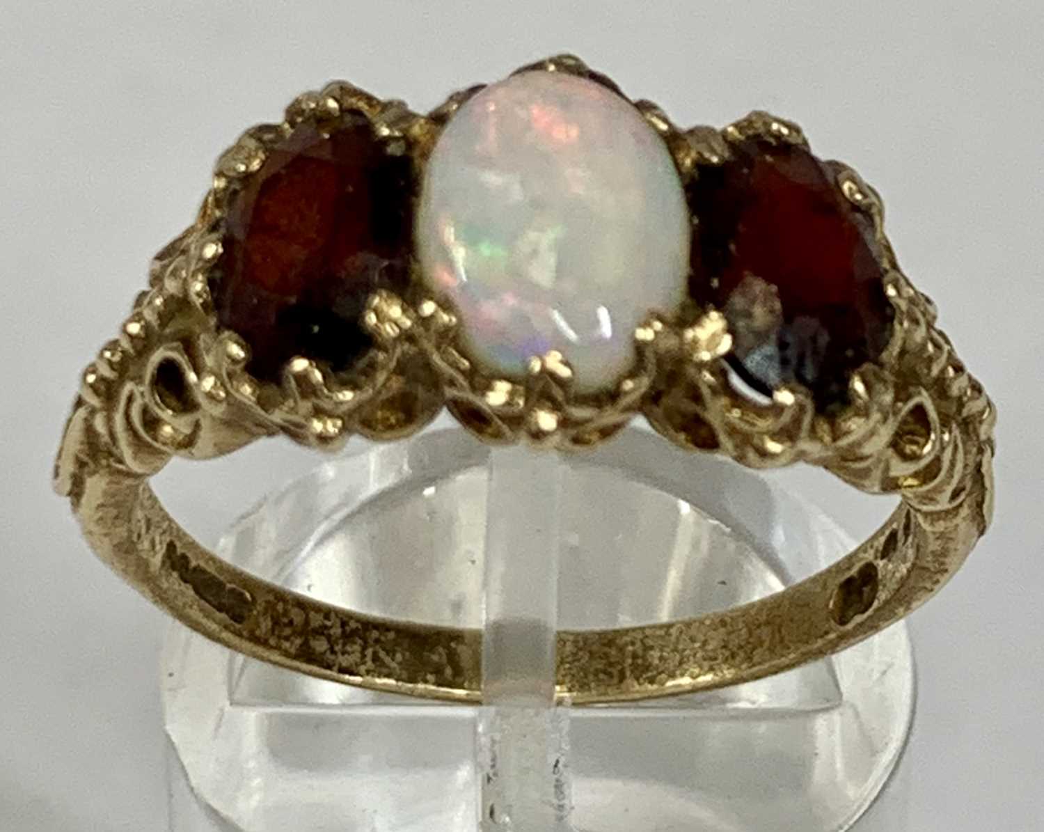 9CT GOLD RING set with oval opal, flanked by oval garnets, size S, 4.0gms Provenance: deceased