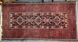 PERSIAN RED GROUND HANDMADE WOOL RUG, triple medallion centre, wide geometric border, 196 x 98cms