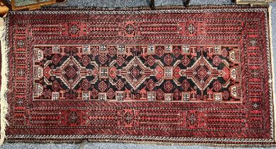 PERSIAN RED GROUND HANDMADE WOOL RUG, triple medallion centre, wide geometric border, 196 x 98cms