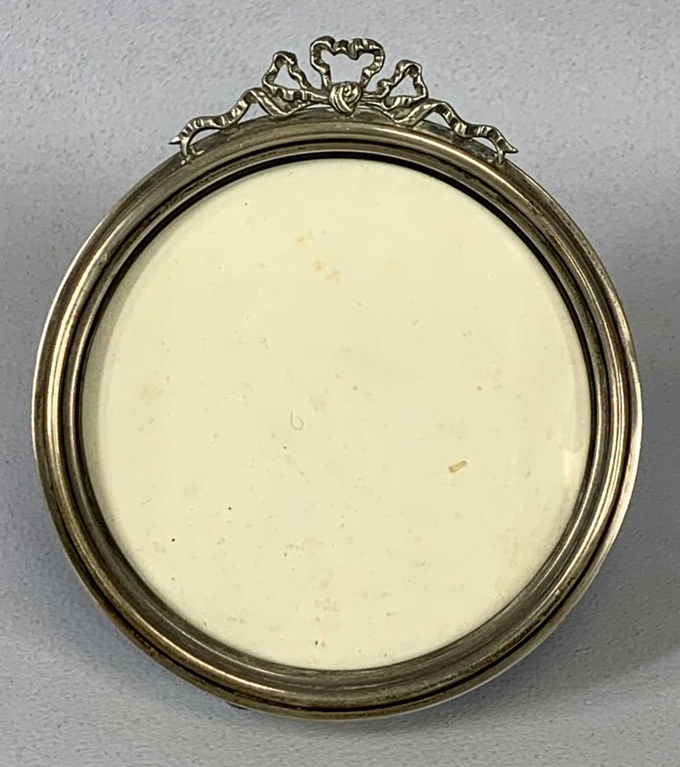 GEORGE V CIRCULAR SILVER PHOTOGRAPH FRAME, capped with a ribbon surmount, with plush easel back,