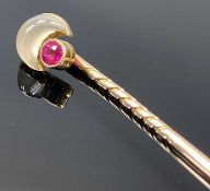 UNMARKED GOLD STICKPIN set with a crescent shaped moonstone and a ruby, 6cms (l), 2.2gms, in