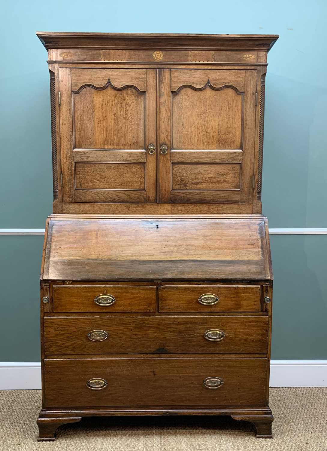 18TH CENTURY OAK BUREAU CABINET, cavetto cornice and marquetry frieze above shaped panel doors and