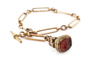 9CT GOLD ALBERT CHAIN, trombone link, T-bar, with yellow metal carnelian intaglio fob, 35.5cms long,