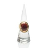 9CT GOLD & CABOCHON GARNET RING, oval set stone within engraved scroll border, hallmarked for London