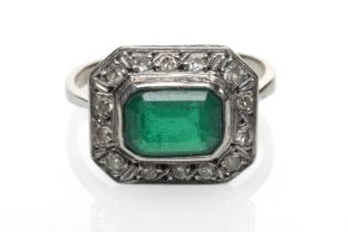 WHITE METAL EMERALD & DIAMOND CHIP CLUSTER RING, the central emerald (8 x 6mms) within a border of