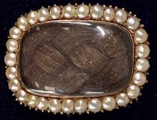 GEORGE III YELLOW METAL MOURNING BROOCH of convex form, glazed plaited hair panel within border of