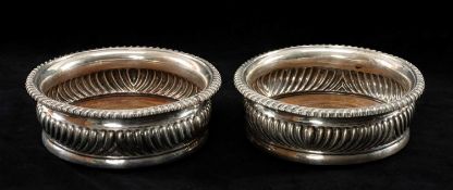 PAIR OF GEORGE III SILVER BOTTLE COASTERS, circular with turned wooden bases, engraved family crest,