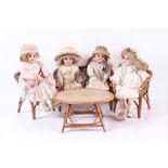 Vier Puppen auf Sitzgruppe.