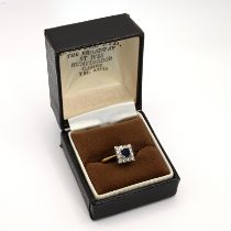 A sapphire and diamond 18 carat gold cluster ring, the square cut sapphire enclosed bob twelve br...