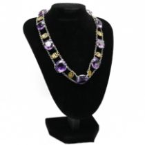 An amethyst necklace, the eleven graduated round cuts set in white metal with metal flower
motifs...