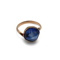A gold single stone synthetic sapphire ring, finger size M unmarked.