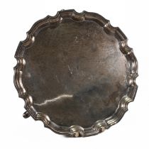 A silver salver, Aide Brothers, Birmingham 1932, with a shaped moulded rim, on three supports, mo...