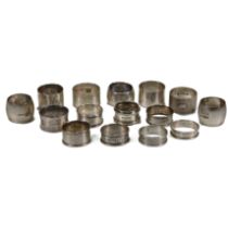 A collection of fifteen silver napkin rings, including one pair, various dates, makers and styles...