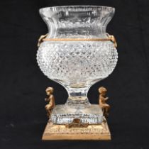 A thistle head shaped Empire style crystal glass urn with a square base raised on a gilt brass st...