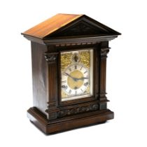 An early 20th Century walnut cased bracket clock in architectural form with carved corinthian pil...
