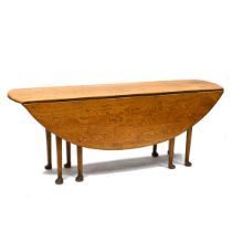 A 20th Century reproduction of a Georgian style wake table in mid oak, supported on eight legs wi...