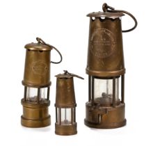 Three brass miner's lamps the tallest 23cm by Eccles, the next 17cm by the Lamp & Limelight Co, H...