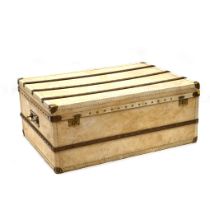 A vintage oversized brass and oak bound trunk with faux velum exterior and cloth lined empty inte...