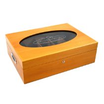 A large fruitwood display humidor, the hinged lid having an oval cut out within which a glass vie...