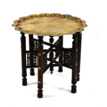 An antique Indian Benares table with a scallop-edged brass top intricately chased with scrollwork...