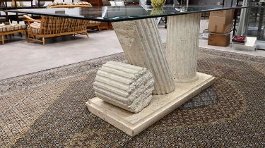 Glass topped dining table supported on a heavy plaster plinth of broken Greco-Roman style columns...