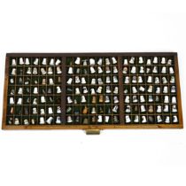 A collection of 148 thimbles, including silver examples, displayed in a printer's typesetting dra...