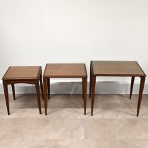 Mid century teak nest of three tables of rectangular form, each with inset glass protectors, rais...