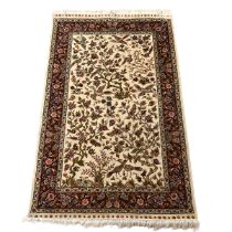 Indian hand woven Isfahan silk warp rug, cream ground with birds in fruit trees surround by a dar...