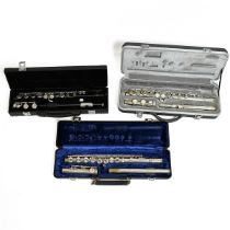 Three flutes in hard cases. 1x 'Slade, Made in USA' with black finish; 1x 'Artley, USA' in silver...