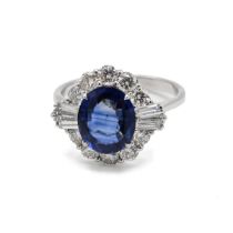An 18k white gold sapphire and diamond cluster ring, set with an oval mixed cut sapphire 2.83cts,...