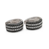 A pair of 14k white gold and diamond huggie earrings, set with four alternating rows of black and...