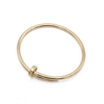 Cartier - An 18ct yellow gold 'Juste un Clou' hinged bangle, signed Cartier, numbered '18 HRE182'...