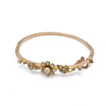 A 20th century gold cultured and seed pearl bangle, with flower head bud and leaves, 11.94 grams....