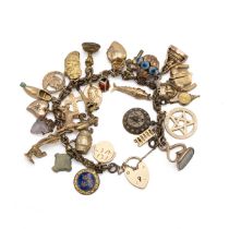 A gilt metal charm bracelet, set with a 9ct gold padlock charm along with various other 9ct, 18ct...
