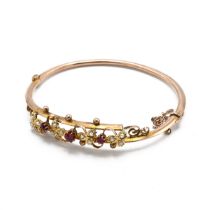 A Victorian-style seed pearl and ruby bangle, set with three central rubies and seed pearl three-...