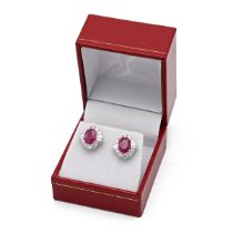 A pair of 18k white gold ruby and diamond oval cluster earrings, set with oval mixed cut rubies w...