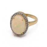 A 14k yellow gold opal and diamond oval dress ring, set with an oval cabochon opal, within a bord...
