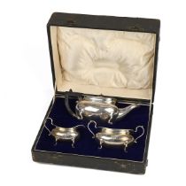 A George V silver three piece tea set, each piece with outstretched legs, the teapot with an ebon...