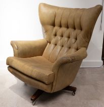 A mid-century G Plan 'Blofeld' model 62 swivel armchair, upholstered in light brown material, on ...